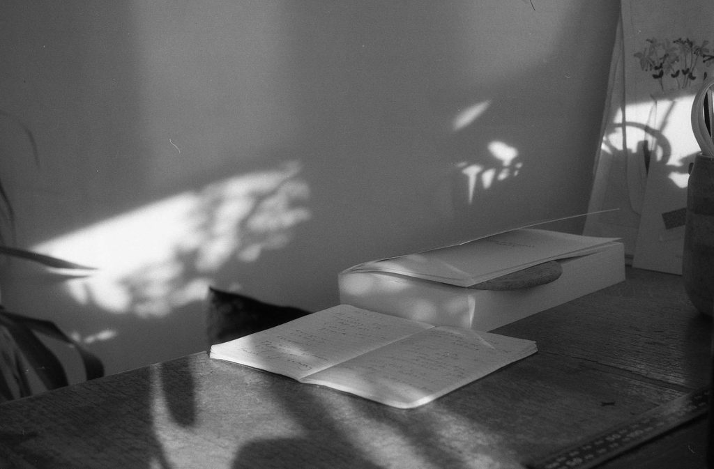 A black and white photo of a desk with books and notebooks on it