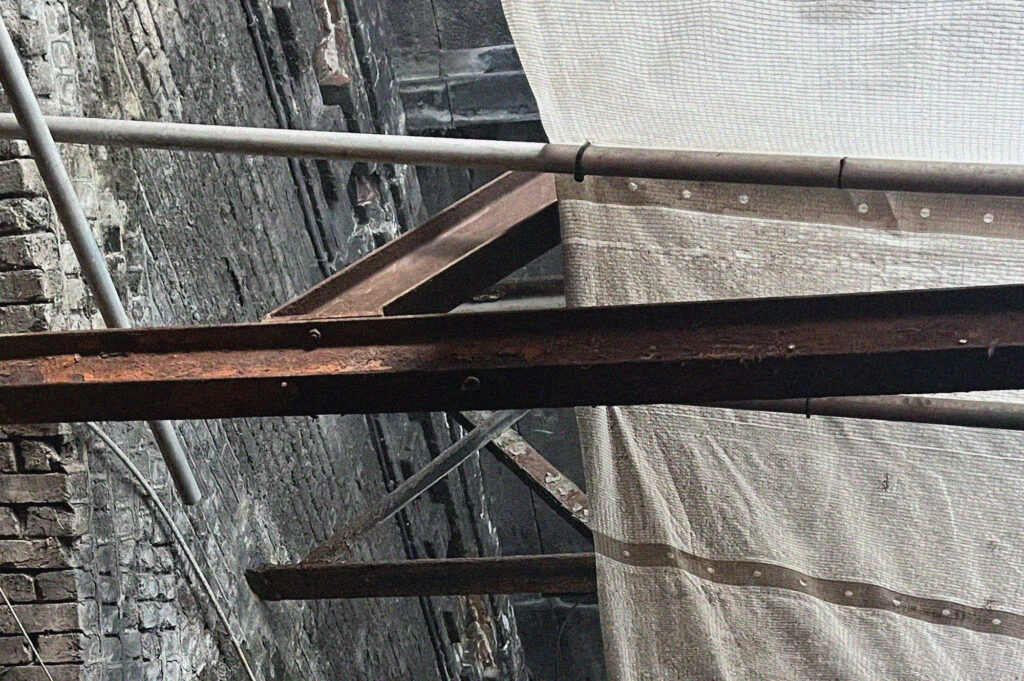 A rusty iron girder in a brick bridge construction site